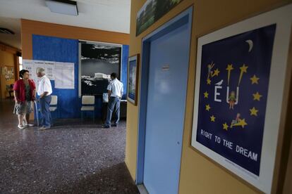 Una pareja de votantes llega este domingo a un colegio electoral a votar, junto a un policía que observa una fotografía de la Acrópolis, en Atenas.