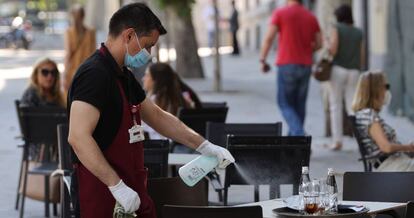 Un camarero desinfecta una mesa tras las marcha de los clientes en Madrid.