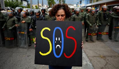 Una mujer sostiene un cartel cerca de la embajada de Cuba en Caracas (Venezuela).