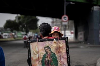 Un hombre carga a una niña y a una imagen de la Virgen de Guadalupe.