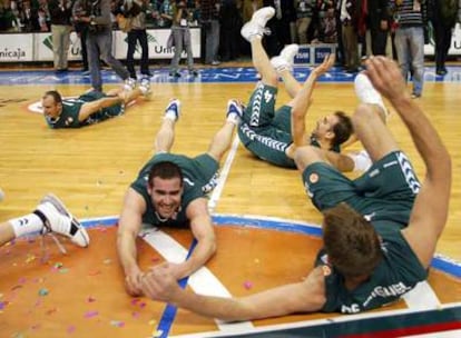 Los jugadores del Unicaja se deslizan por el parqué del pabellón para celebrar su victoria.