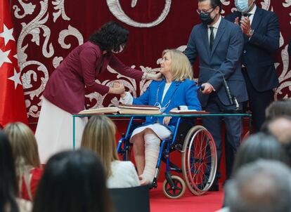 La presidenta madrileña, Isabel Díaz Ayuso (izqda.) saluda a la consejera de Familia, Juventud y Política Social, Concepción Dancausa, que es ayudada con su silla de ruedas por el consejero de Hacienda y Función Pública, Javier Fernández-Lasquetty, el 21 de junio durante la toma de posesión de los nuevos consejeros del Gobierno de la Comunidad de Madrid en la Real Casa de Correos.