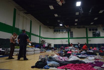 Membros da Policial observam a pessoas em um dos refúgios anti furacão de Miami.