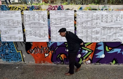 Un hombre de avanzada edad pasea delante de las listas de elecciones en un centro de votaciones en Atenas.