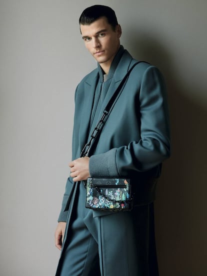 El modelo viste conjunto monocromo de Louis Vuitton y bolso con cadena y estampado floral de la misma firma.