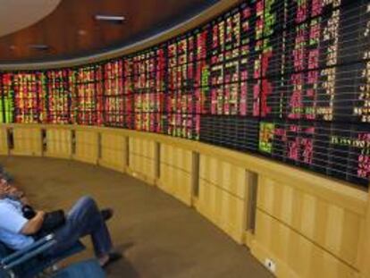Un corredor de bolsa observa los paneles informativos en Bangkok (Tailandia). EFE/Archivo