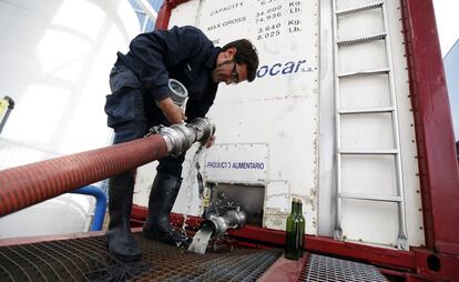 Un trabajador conecta una manguera a un camión que partirá hacia Francia desde La Mancha.