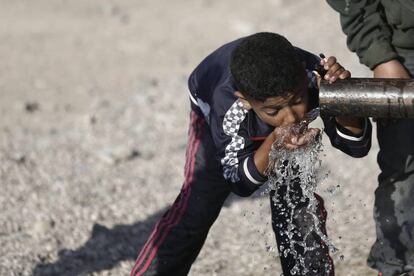 Un niño refugiado toma agua de una tubería en Idomeni, cerca la frontera de Grecia con Macedonia, el 20 de abril de 2016.