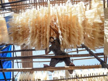 Un trabajador seca fideos en la India.