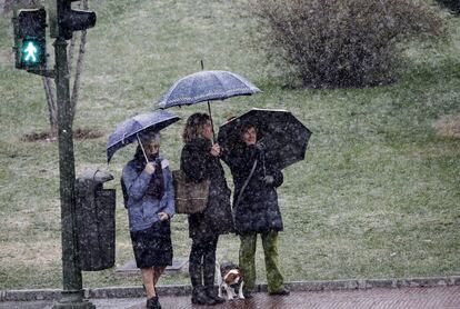 En la plaza de San Juan de la Cruz, tres mujeres se protegen con paraguas de la nieve que ha comenzado a caer hoy en la capital. El termómetro oscilará en Madrid capital entre los -2 y los 8 grados.