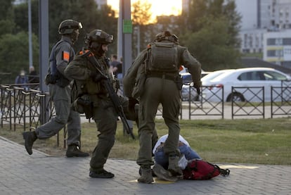 Dos policías golpean a un manifestante, tendido sobre el suelo.