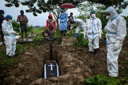 Un grupo de voluntarios con equipos de protección individual (EPI) entierra a una presunta víctima del coronavirus en un cementerio en el distrito de Taungoo en la región de Bago de Myanmar.