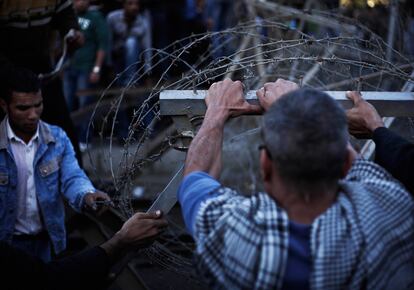 Un manifestante trata de romper los alambres de espino que protegen el palacio presidencial.