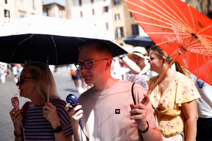 Dos turistas utilizan unos pequeños ventiladores y sombrillas para protegerse del calor en Roma, este miércoles.