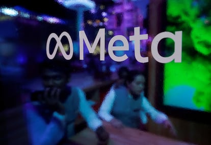 People are seen behind a logo of Meta Platforms, during a conference in Mumbai, India, September 20, 2023.