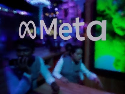 People are seen behind a logo of Meta Platforms, during a conference in Mumbai, India, September 20, 2023.