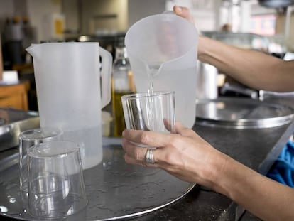 Una mujer echa agua en un vaso.