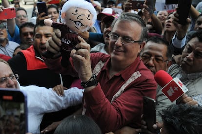 Marcelo Ebrard sostiene un muñeco que representa a López Obrador.