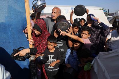 Palestinos desplazados esperan para recibir comida en un punto de distribución del refugio de Naciones Unidas, este jueves en Jan Yunis.