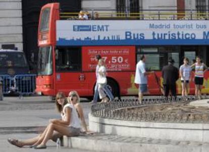 Dos jóvenes turistas descansan junto a la fuente de la Puerta del Sol. EFE/Archivo