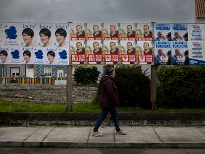 Una persona pasa junto a carteles con propaganda electoral en A Illa de Arousa (Pontevedra).