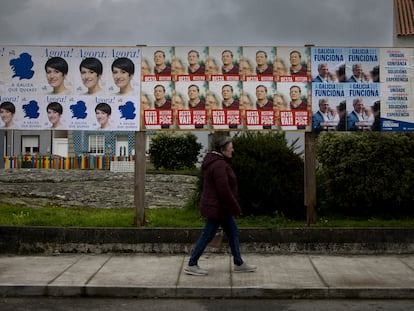 Una persona pasa junto a carteles con propaganda electoral en A Illa de Arousa (Pontevedra).