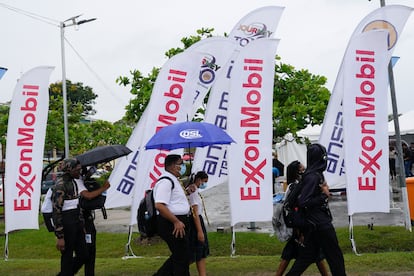 Estudiantes de secundaria caminan junto a banderolas de ExxonMobil en una feria de empleo en la Universidad de Guyana en Georgetown.