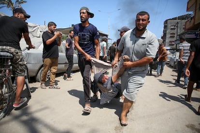 Dos hombres trasladan a una mujer herida tras el bombardeo israelí en Al Mawasi, este sábado. 