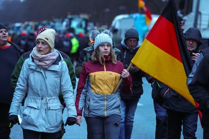 Una persona sostiene una bandera alemana mientras los agricultores protestan contra el recorte de los subsidios fiscales a los vehículos en Berlín