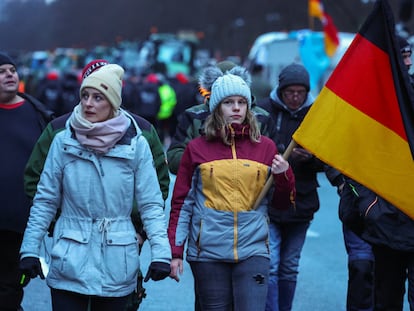 Una persona sostiene una bandera alemana mientras los agricultores protestan contra el recorte de los subsidios fiscales a los vehículos en Berlín