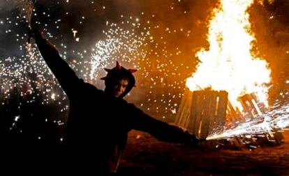 Un 'dimoni' baila ante una hoguera de Sant Joan en el centro de Barcelona celebrando la llegada del verano.