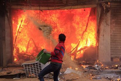 Un civil intenta apagar las llamas en una tienda de ropa incendiada por los partidarios de la hermandad musulmana durante enfrentamientos con los opositores de Morsi, en Gizeh, Egipto.