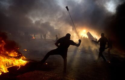 Palestinos lanzan piedras entre el humo de los neumáticos quemados, el 12 de octubre de 2018, en la Franja de Gaza.  