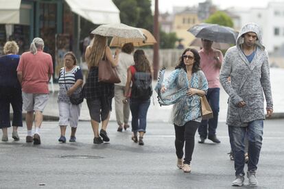 "Los chubascos más importantes caídos hasta ahora han sido tormentosos en el sur y sureste y de madrugada", precisa sobre las diez de la mañana un portavoz de la Aemet. En la imagen, varias personas se protegen de la lluvia en las calles de Sevilla, el 17 de octubre de 2017.