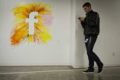 Un empleado camina por un muro con el logo de la red social Facebook en la nueva sede de la compañía en Menlo Park, California (EEUU). EFE/Archivo