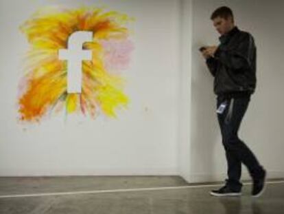 Un empleado camina por un muro con el logo de la red social Facebook en la nueva sede de la compañía en Menlo Park, California (EEUU). EFE/Archivo