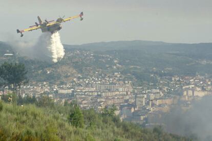 Un hidroavión intenta sofocar el fuego sobre una de las colinas junto a la ciudad de Ourense.