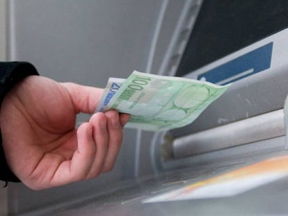 Una persona saca euros de un cajero automático.
