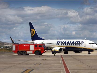 Un cami&oacute;n de bomberos pasa junto a un avi&oacute;n de Ryanair en el aeropuerto de Manises, Valencia.