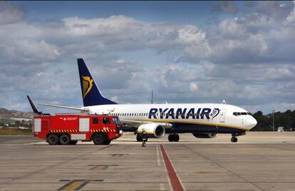 Un cami&oacute;n de bomberos pasa junto a un avi&oacute;n de Ryanair en el aeropuerto de Manises, Valencia.