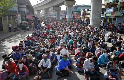 Una multitud de trabajadores migrantes y sus familias esperan el transporte para llegar a una estación de ferrocarril, donde el tren les lleva a su Estado natal de Uttar Pradesh (India).