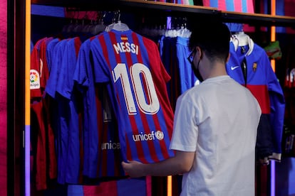Un aficionado mira una camiseta de Messi en una tienda de Barcelona.