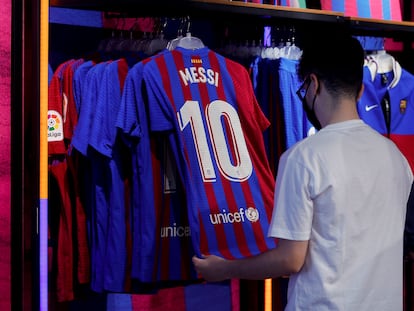 Un aficionado mira una camiseta de Messi en una tienda de Barcelona.