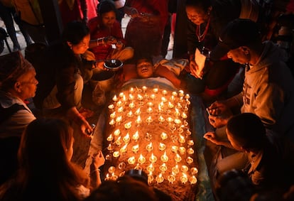 Un devoto yace cubierto con lámparas de aceite colocadas por otros devotos mientras ofrece oraciones como parte de un ritual durante "Dashain", un festival religioso hindú, en Bhaktapur (Nepal).