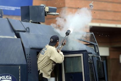 Un antidisturbios dispara bombas de gas lacrim&oacute;geno.