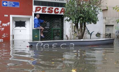Un hombre espera ser rescatado en una calle de Buenos Aires tras las intensa lluvias caídas.