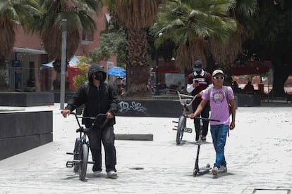 En este nivel de alerta, se recomienda a las poblaciones vecinas evitar cualquier actividad al aire libre. En la imagen, tres personas circulan con sus bicicletas y patinetes en un parque de la ciudad de Puebla cubierto de ceniza volcánica, este domingo.  