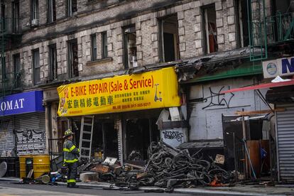 A firefighter looks through debris in the aftermath of a fire which authorities say started at an e-bike shop and spread to upper-floor apartments, Tuesday June 20, 2023, in New York.