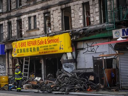 A firefighter looks through debris in the aftermath of a fire which authorities say started at an e-bike shop and spread to upper-floor apartments, Tuesday June 20, 2023, in New York.