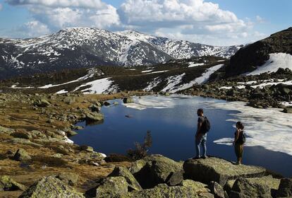 Turistas visitan la Laguna de Peñalara, todavía con algo de hielo.